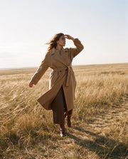 Manteau laine coupe oversize porté par une femme, vue de trois-quarts, vent, champ