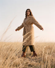 Manteau laine coupe oversize porté par une femme, silhouette entière, champ, bras écartés