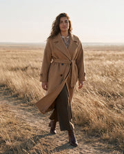 Manteau laine coupe oversize porté par une femme, silhouette entière, herbes hautes, ceinture