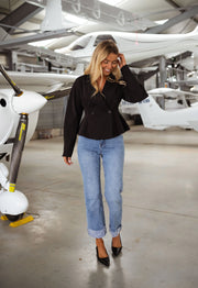 Blazer cintré à épaulettes noir porté par une femme, vue de face, hangar, jean clair