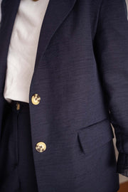 Blazer doublé à épaulettes bleu porté par une femme, vue rapprochée, boutons dorés, revers