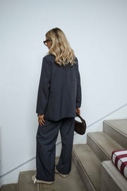 Blazer doublé à épaulettes gris porté par une femme, vue de dos, escalier, pantalon assorti