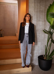 Blazer doublé à épaulettes noir porté par une femme, silhouette entière, plante, jean