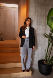 Blazer doublé à épaulettes noir porté par une femme, silhouette entière, escalier, plante
