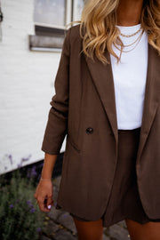 Blazer ample doublé à épaulettes chocolat porté par une femme, vue rapprochée, t-shirt blanc, mur blanc