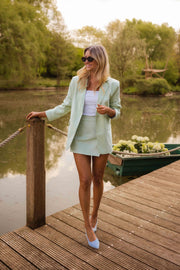 Blazer doublé à épaulettes vert porté par une femme, silhouette entière, ponton, rambarde