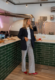 Blazer long doublé ample bleu porté par une femme, silhouette entière, comptoir, escarpins rouges