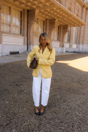 Blazer rayé cintré à épaulettes porté par une femme, silhouette entière, pantalon blanc, sac à l'épaule