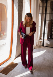 Blazer droit doublé à épaulettes bordeaux porté par une femme, silhouette entière, pochette, jambes écartées