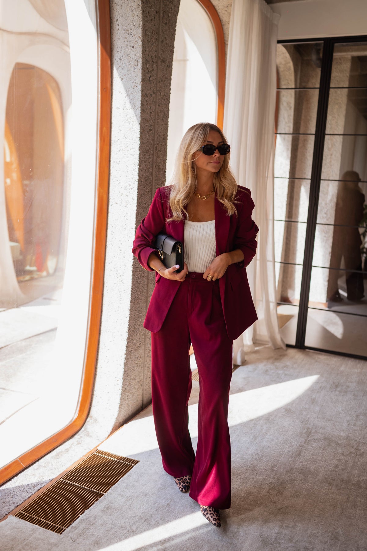 Blazer droit doublé à épaulettes bordeaux porté par une femme, silhouette entière, pantalon bordeaux, pochette