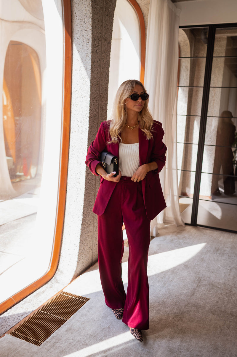 Blazer droit doublé à épaulettes bordeaux porté par une femme, silhouette entière, pantalon bordeaux, pochette