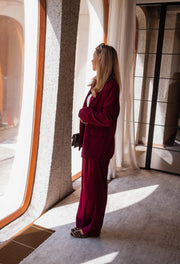 Blazer droit doublé à épaulettes bordeaux porté par une femme, silhouette entière, pantalon bordeaux, rideaux