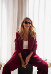 Blazer droit doublé à épaulettes bordeaux porté par une femme, assise, assise, lunettes