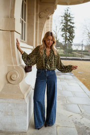 Blouse à pois col V portée par une femme, vue de face, colonnade, jean large