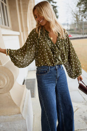 Blouse à pois col V portée par une femme, vue de trois-quarts, manches bouffantes, sac
