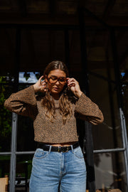 Blouse léopard à manches évasées portée par une femme, vue de face, lunettes, ceinture marron