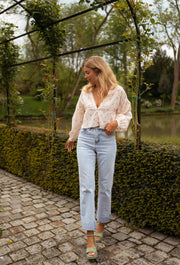 Blouse fleurie à décolleté dentelle portée par une femme, silhouette entière, pergola, chemin pavé