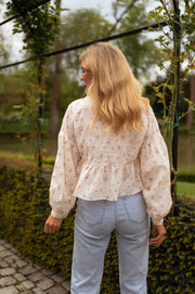 Blouse fleurie à décolleté dentelle portée par une femme, vue de dos, jardin, jean clair