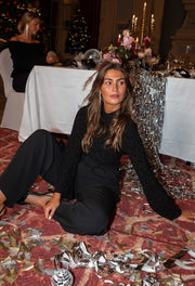 Blouse ajustée à col montant noire portée par une femme, assise, assise au sol, confettis