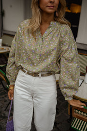 Blouse fleurie légèrement évasée portée par une femme, vue rapprochée, manches bouffantes, ceinture marron