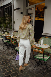 Blouse fleurie légèrement évasée portée par une femme, vue de dos, sac violet, terrasse
