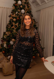 Blouse résille à fleurs brillantes noire portée par une femme, vue de face, sourire, sapin