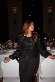 Blouse à dos ouvert boutonné portée par une femme, vue de trois-quarts, table dressée, pantalon noir