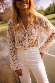 Blouse transparente col V boutonnée écrue portée par une femme, vue de face, étang, pantalon blanc