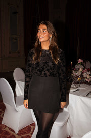 Blouse à fleurs en velours noire portée par une femme, vue de face, table dressée, jupe noire