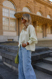 Blouse à carreaux manches ballon portée par une femme, vue de dos, sac vert