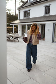 Blouse fluide à col V portée par une femme, en marchant, terrasse, gilet beige