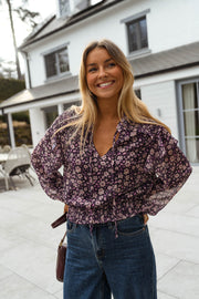 Blouse fluide à col V portée par une femme, vue de face, terrasse, maison blanche