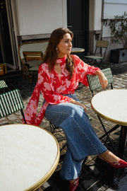 Blouse fluide à col lavallière portée par une femme, assise, à une table, jean