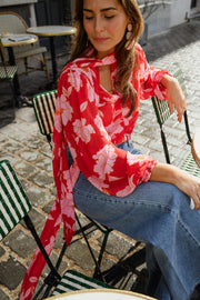 Blouse fluide à col lavallière portée par une femme, vue de trois-quarts, à une table, rue
