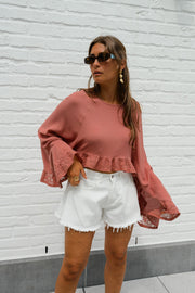 Blouse fluide à manches évasées portée par une femme, vue rapprochée, short blanc, manches évasées