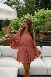 Blouse fluide à manches évasées portée par une femme, vue de trois-quarts, bras écartés, jardin