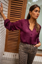 Blouse satinée col V bordeaux portée par une femme, vue de face, volets, bras levé
