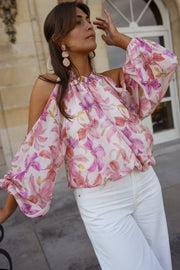 Blouse fleurie à col rond portée par une femme, vue de trois-quarts, manches larges, pantalon blanc