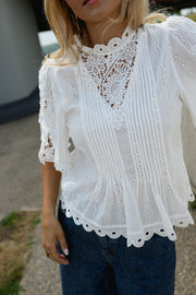 Blouse brodée col montant portée par une femme, gros plan de la broderie et de l'encolure