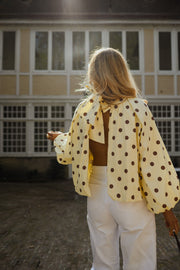 Blouse à pois dos ouvert portée par une femme, vue de dos, dos ouvert, pantalon blanc