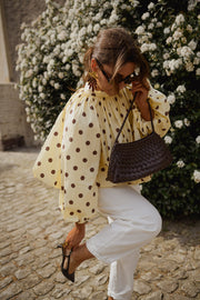 Blouse à pois dos ouvert portée par une femme, vue rapprochée, sac à main, lunettes de soleil