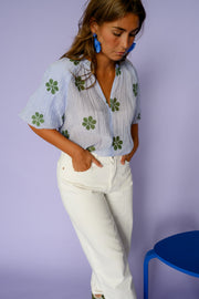 Blouse plissée col V portée par une femme, vue de trois-quarts, mains dans les poches