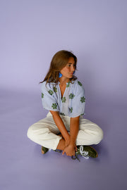 Blouse plissée col V portée par une femme, assise, sur le sol, jambes croisées