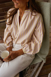 Blouse rayée à manches ballon portée par une femme, assise, tasse, fauteuil