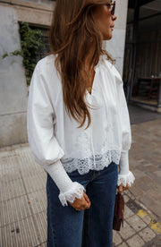 Blouse dentelle à col V blanche portée par une femme, vue de dos, cheveux longs