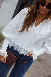 Blouse dentelle à col V blanche portée par une femme, vue rapprochée