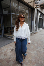 Blouse dentelle à col V blanche portée par une femme, vue de face