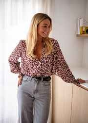 Blouse imprimée fluide portée par une femme, vue de face, rideaux blancs, jean gris