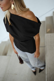 Blouse à épaule dénudée noire portée par une femme, vue rapprochée, épaule dénudée, sac bordeaux