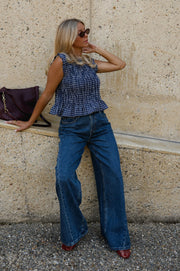 Blouse froncée sans manches portée par une femme, vue de trois-quarts, lunettes de soleil, sac à l'épaule